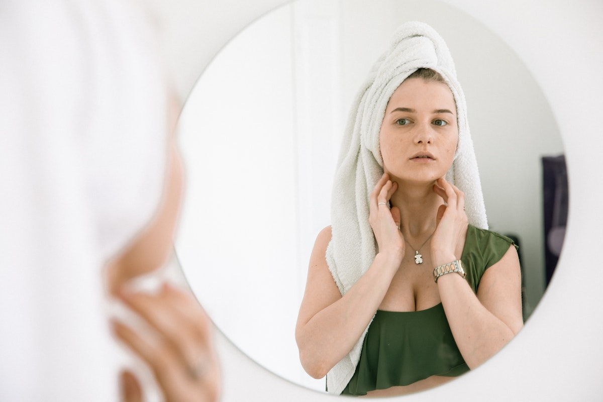 Fiatal nő a nyakát vizsgálja a tükörben. Mi a különbség a mandulagyulladás és a torokgyulladás között?