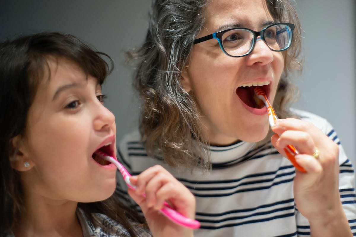 Anyuka és kislánya együtt mosnak fogat. Hogyan fokozza a szívbetegségek kockázatát a fogszuvasodás?